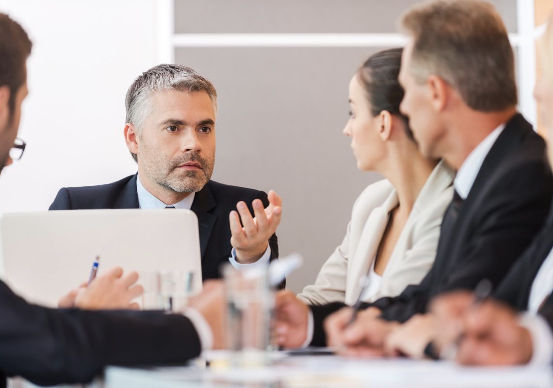 Business meeting. Business people in formalwear discussing something while sitting together at the table